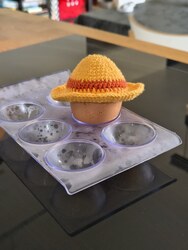 An egg wearing a yellow crochet straw hat with a red band, in the style of One Piece