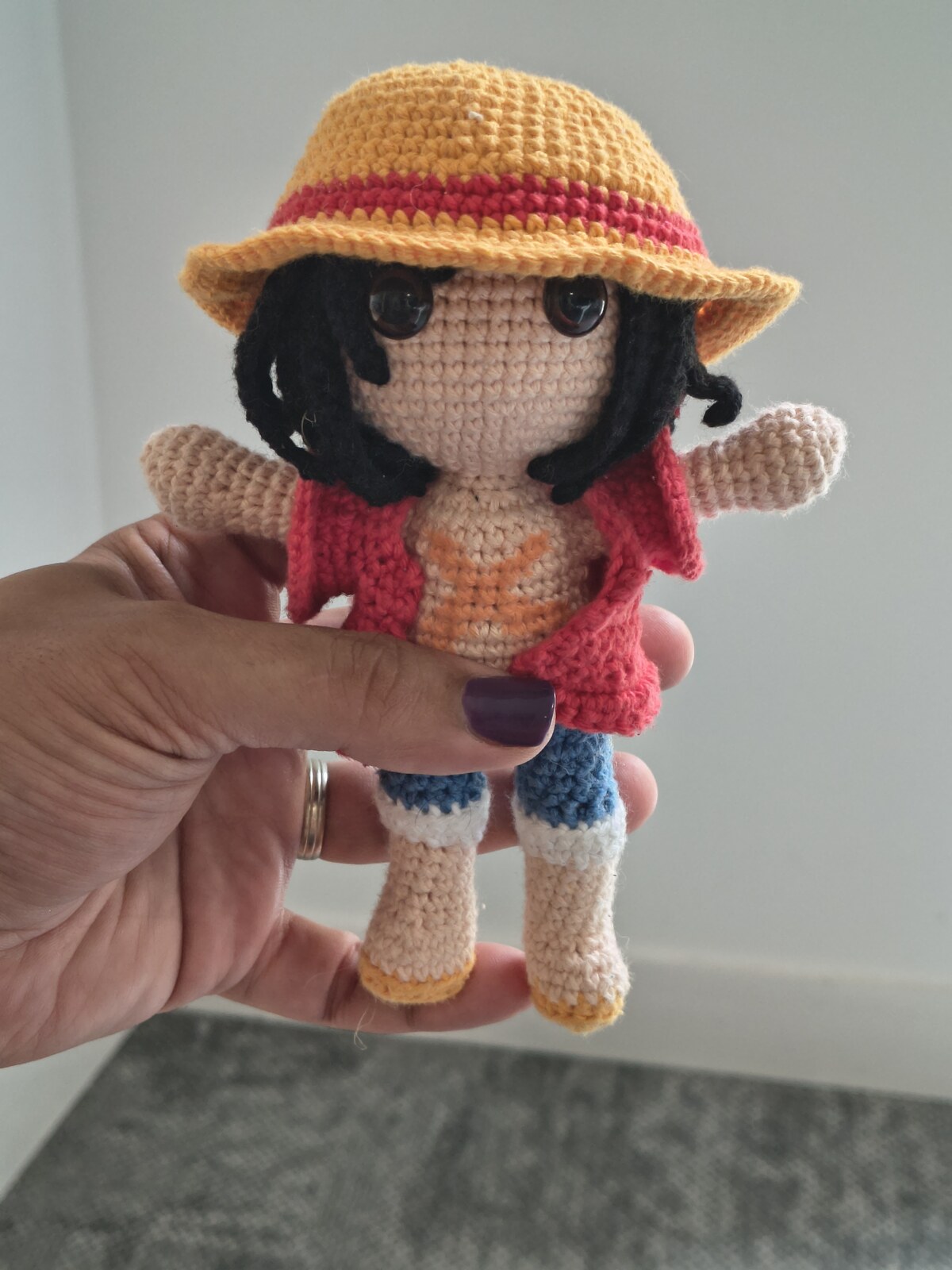 Work in progress: the amigurumi wearing its red vest and straw hat, before the yellow sash was added